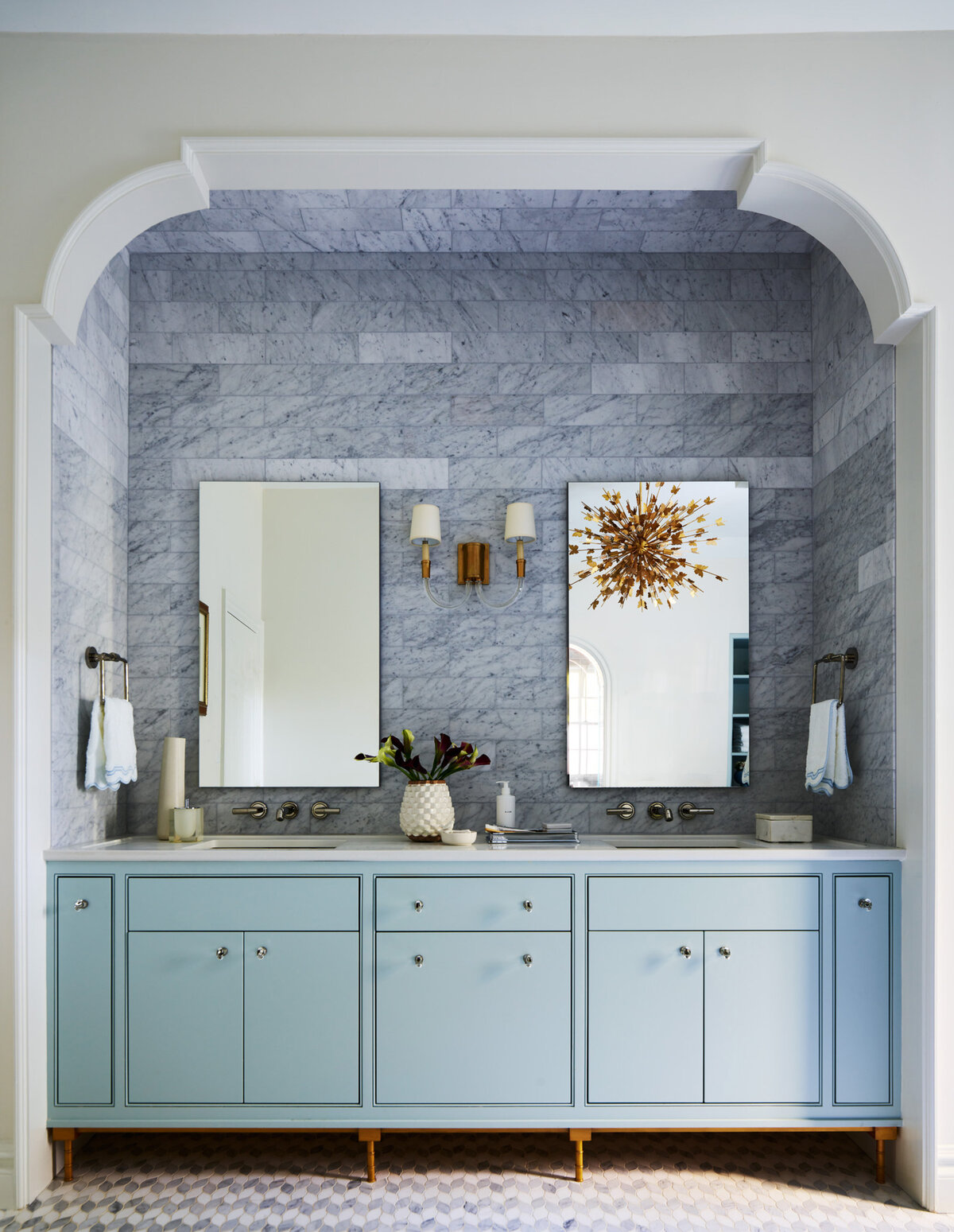 Custom baby blue vanity with crystal hardware, Carrera wall tile, brass lighting, and Kallista plumbing fixtures create a timeless, sophisticated bathroom in Milton.