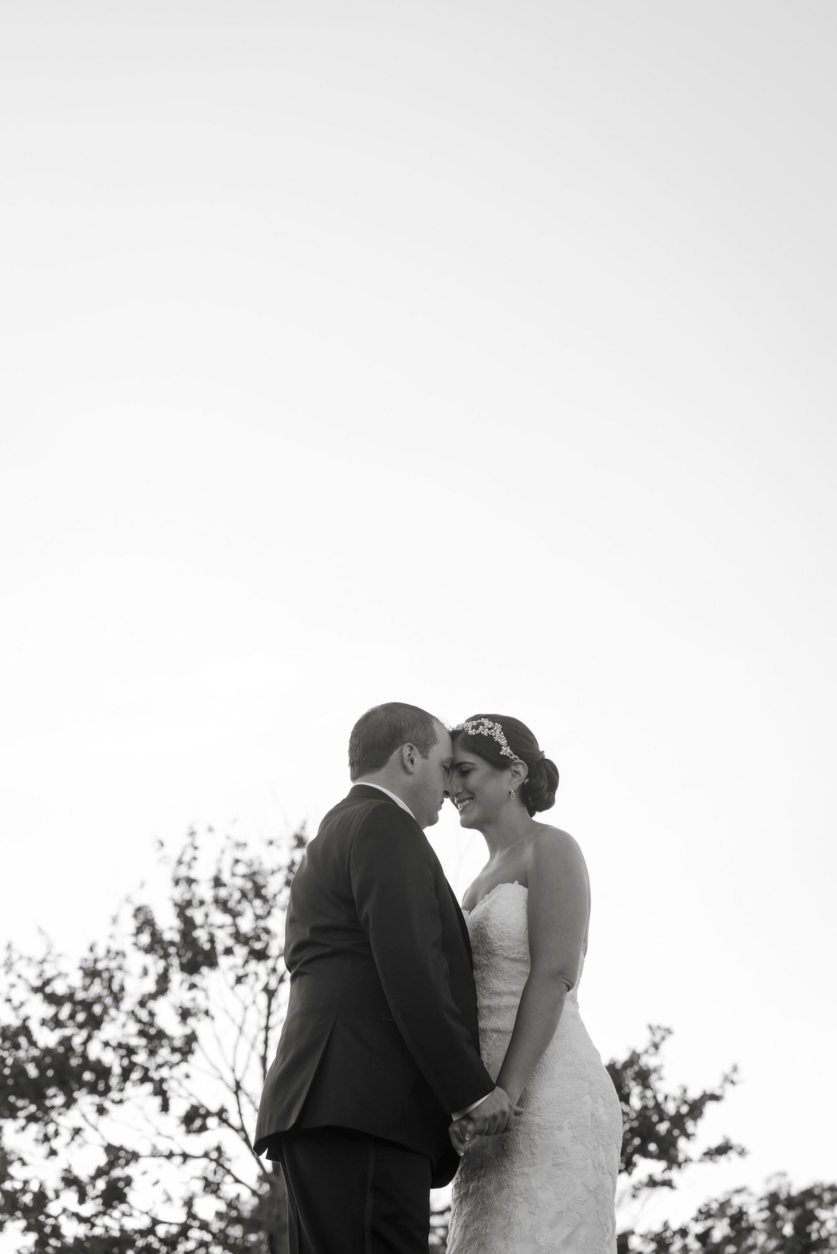 black and white photo of bride and groom touching foreheads and smiling from wedding reception at Lawrence Yacht and Country Club