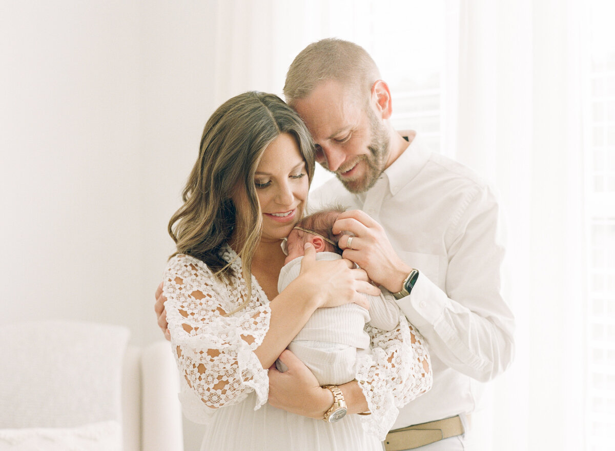 Parents snuggle their new baby during a lifestyle newborn session in Holly Springs NC. Image by Raleigh newborn photographer A.J. Dunlap Photography.