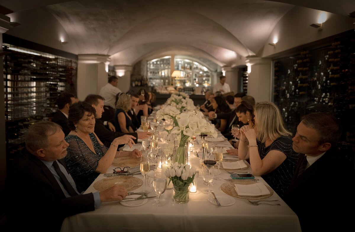Guests enjoy dinner in a candlelit wine cellar.