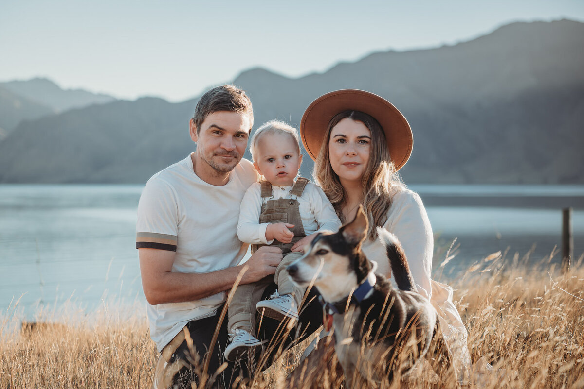 a family posing with lake hawea and mountains in the background during their family photography session in wanaka