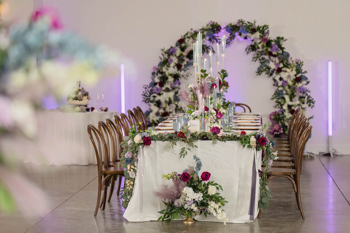 Luxury wedding reception setup featuring a floral arch and candlelit tablescape.