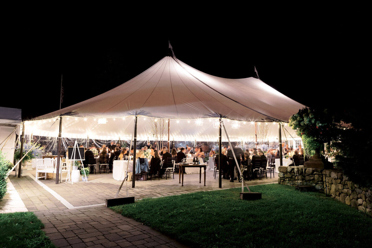 The elegant wedding tent reception at Lion Rock Farm, CT, looks glamorous at night. Image by Jenny Fu Studio