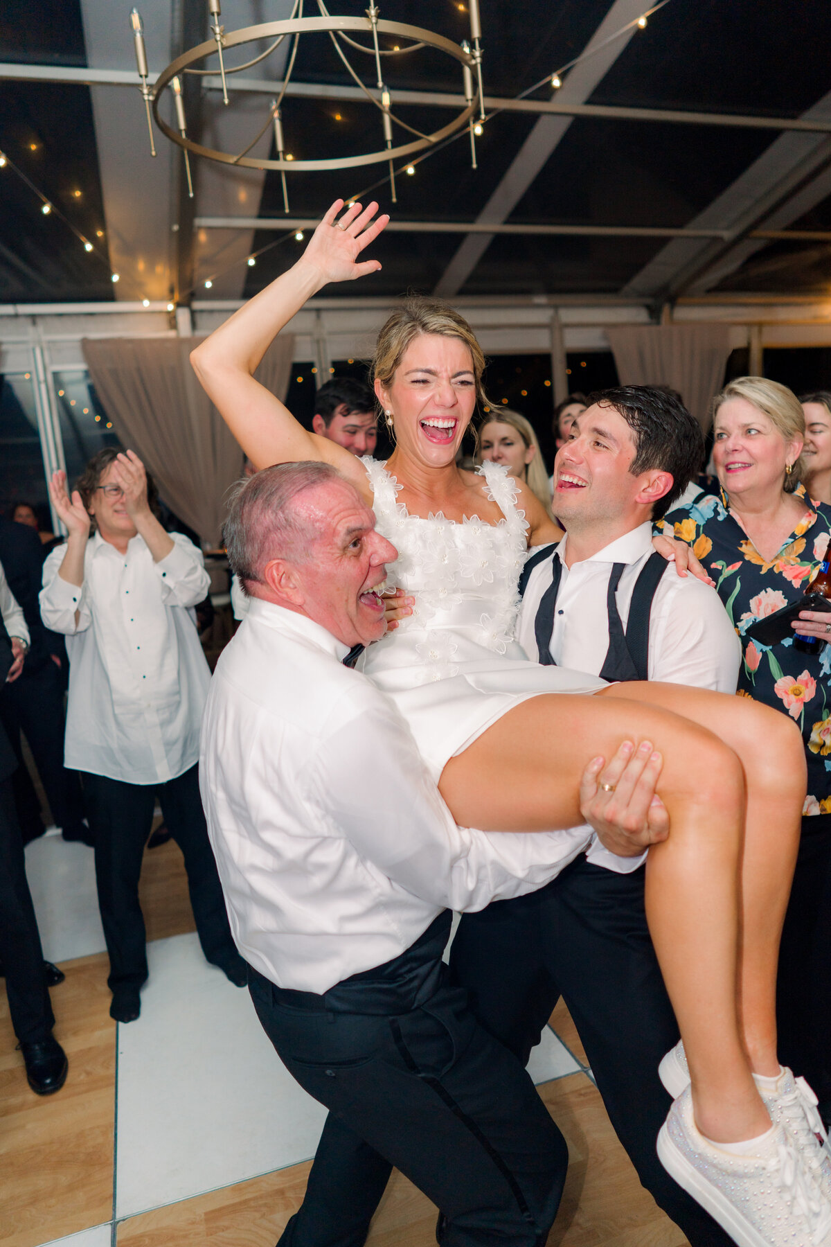 Father of the bride and groom lift up bride on the dance floor at Lowndes Grove wedding. Candid wedding reception flash photos. Charleston based destination wedding photographer.