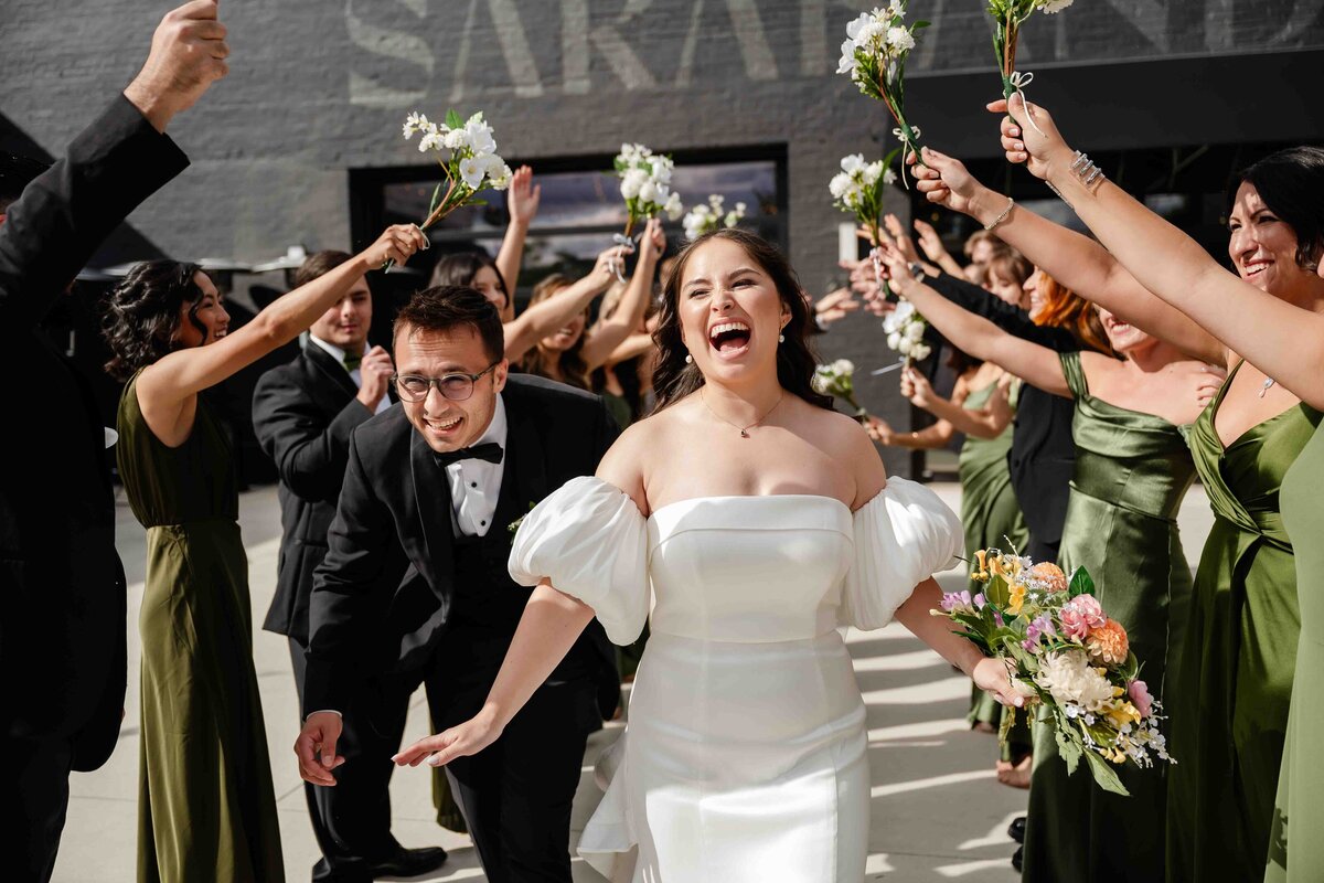 Bride and groom run under a wedding party tunnel 