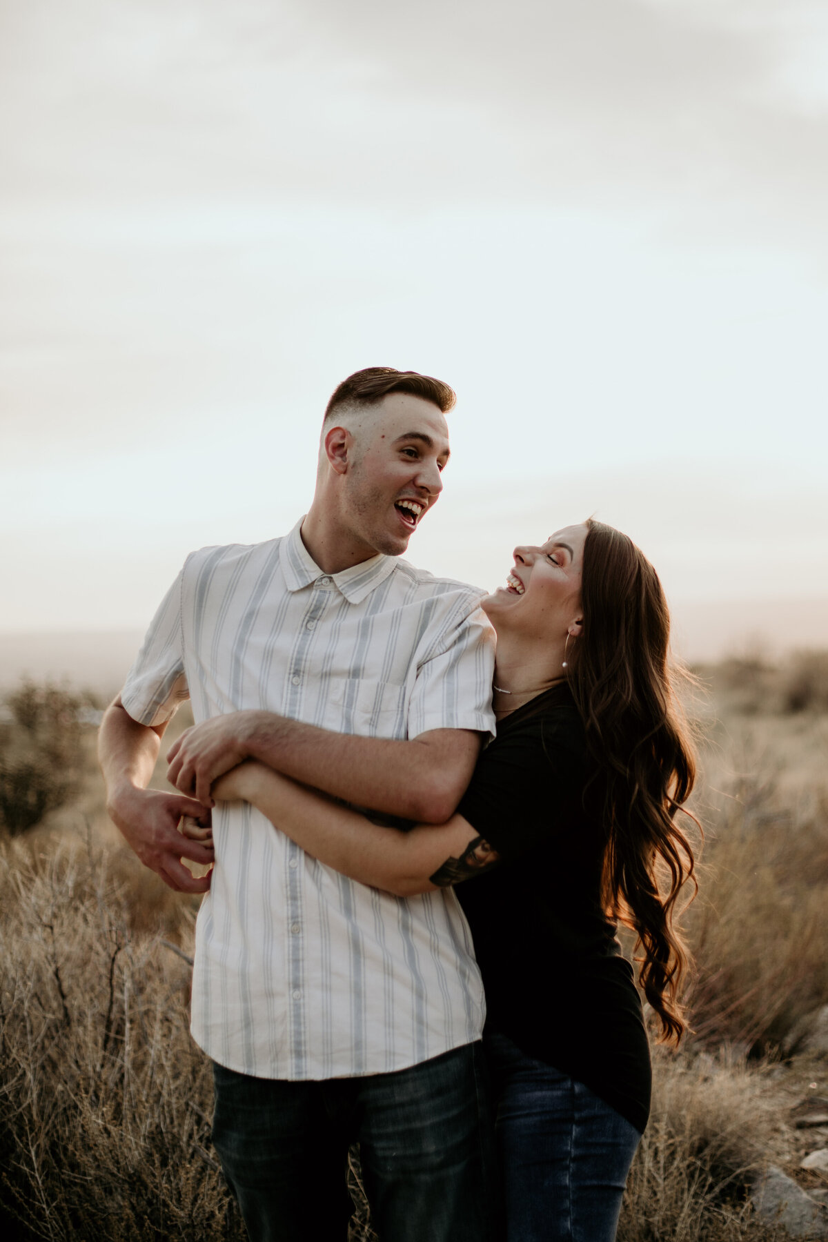 woman hugging fiancé from behind laughing