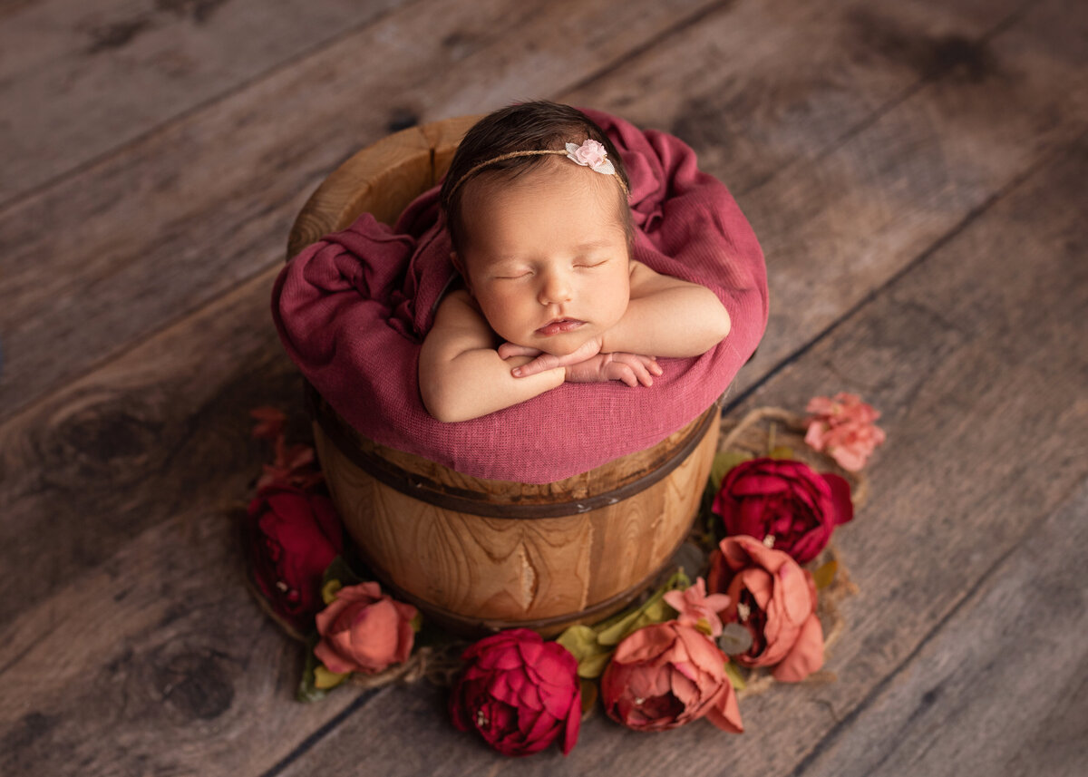 Baby girl at newborn session in bucket with pink flowers