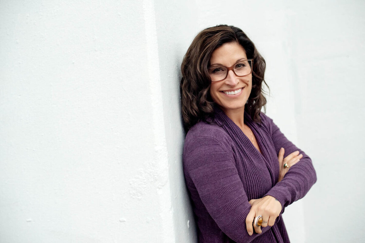 professional head shot of woman in glasses and a purple sweater.