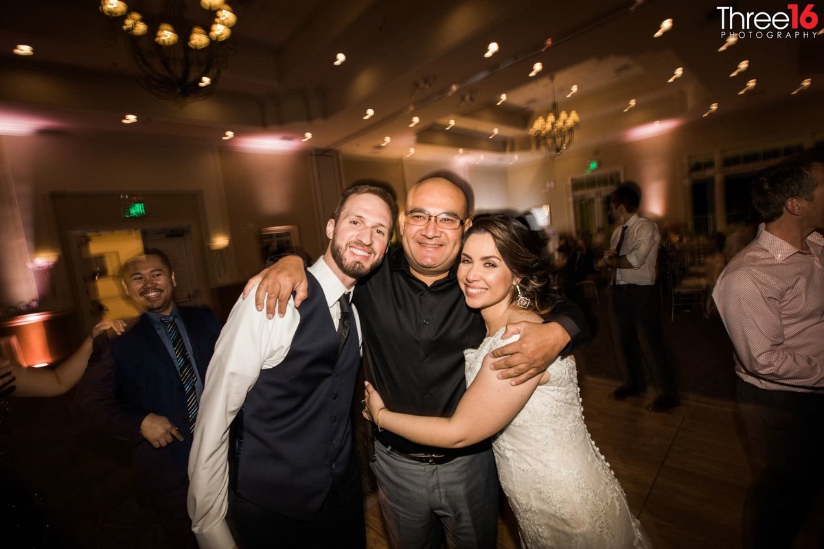 Bride and Groom pose with a guest on the dance floor