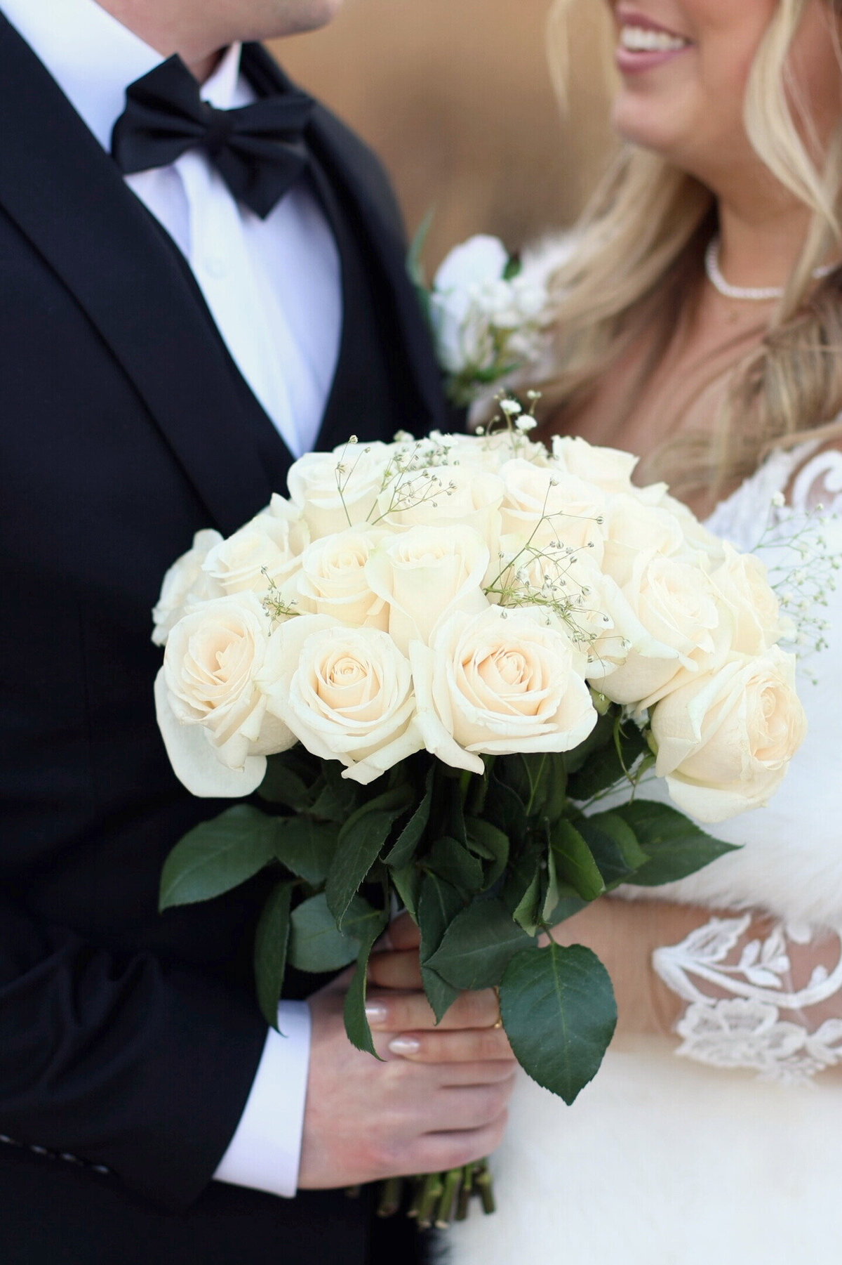 A close up of a bride and groom holding a flower bouquet at a winter wedding