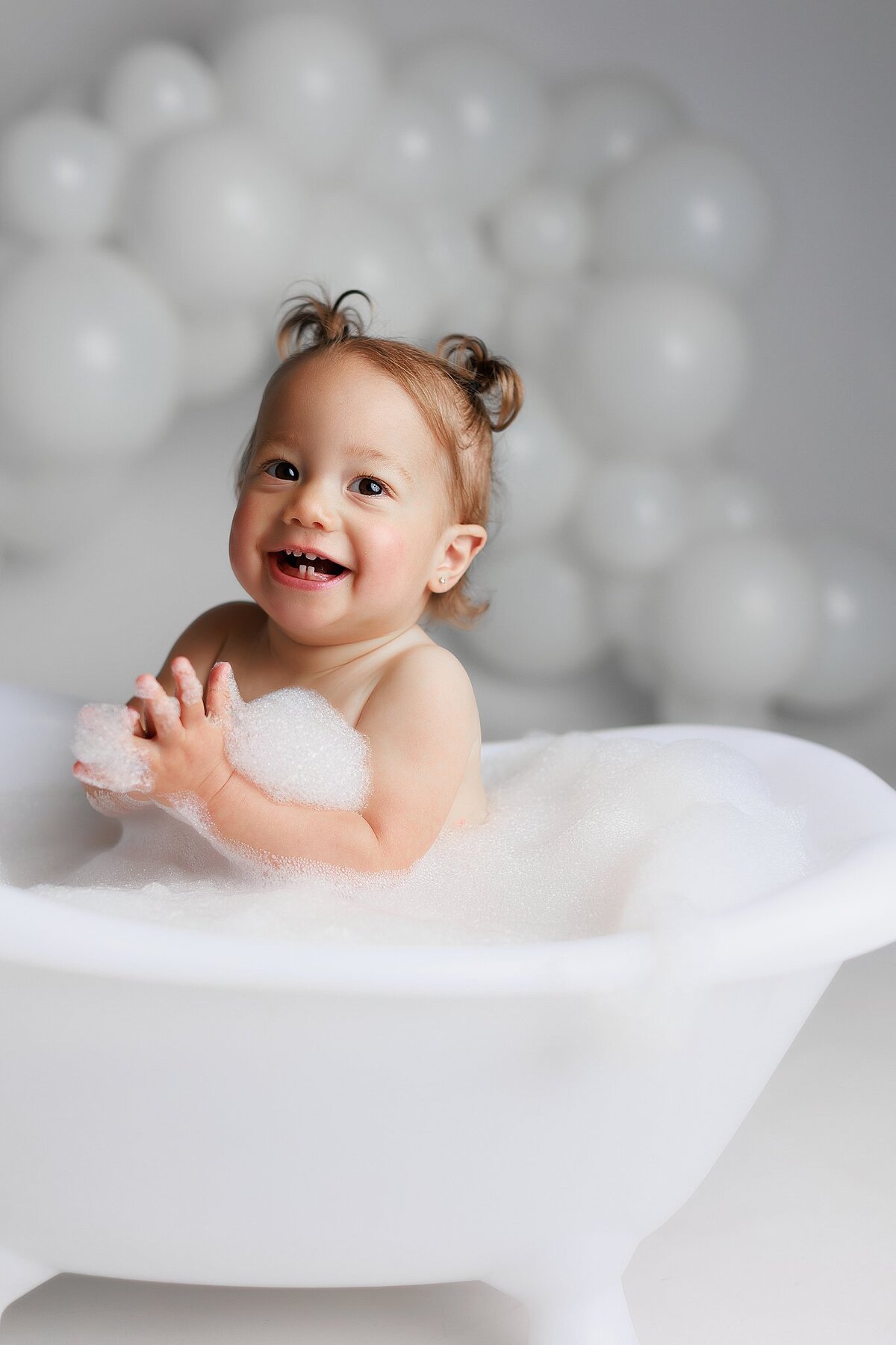 One-year-old baby enjoying a bubble bath during first birthday photoshoot