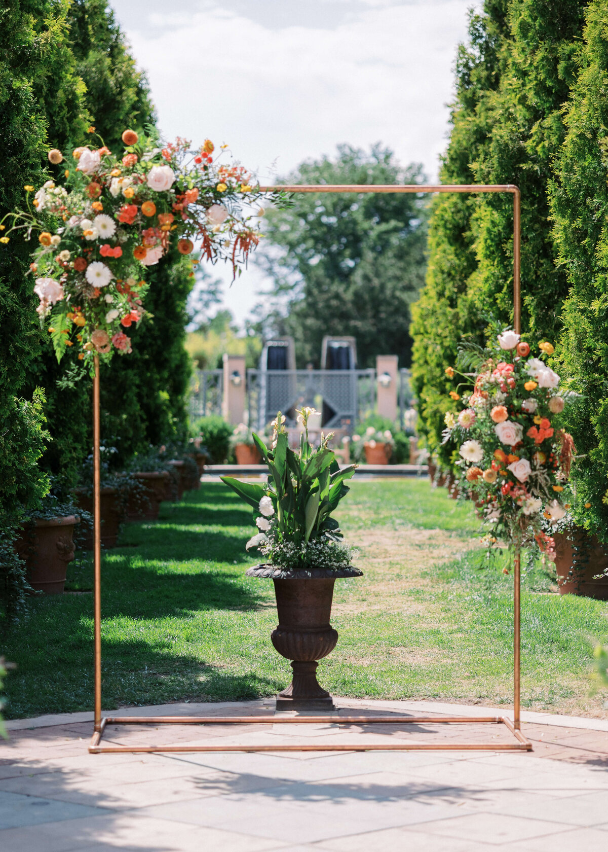 Copper Archway is adorned with floral arrangements at garden wedding ceremony site