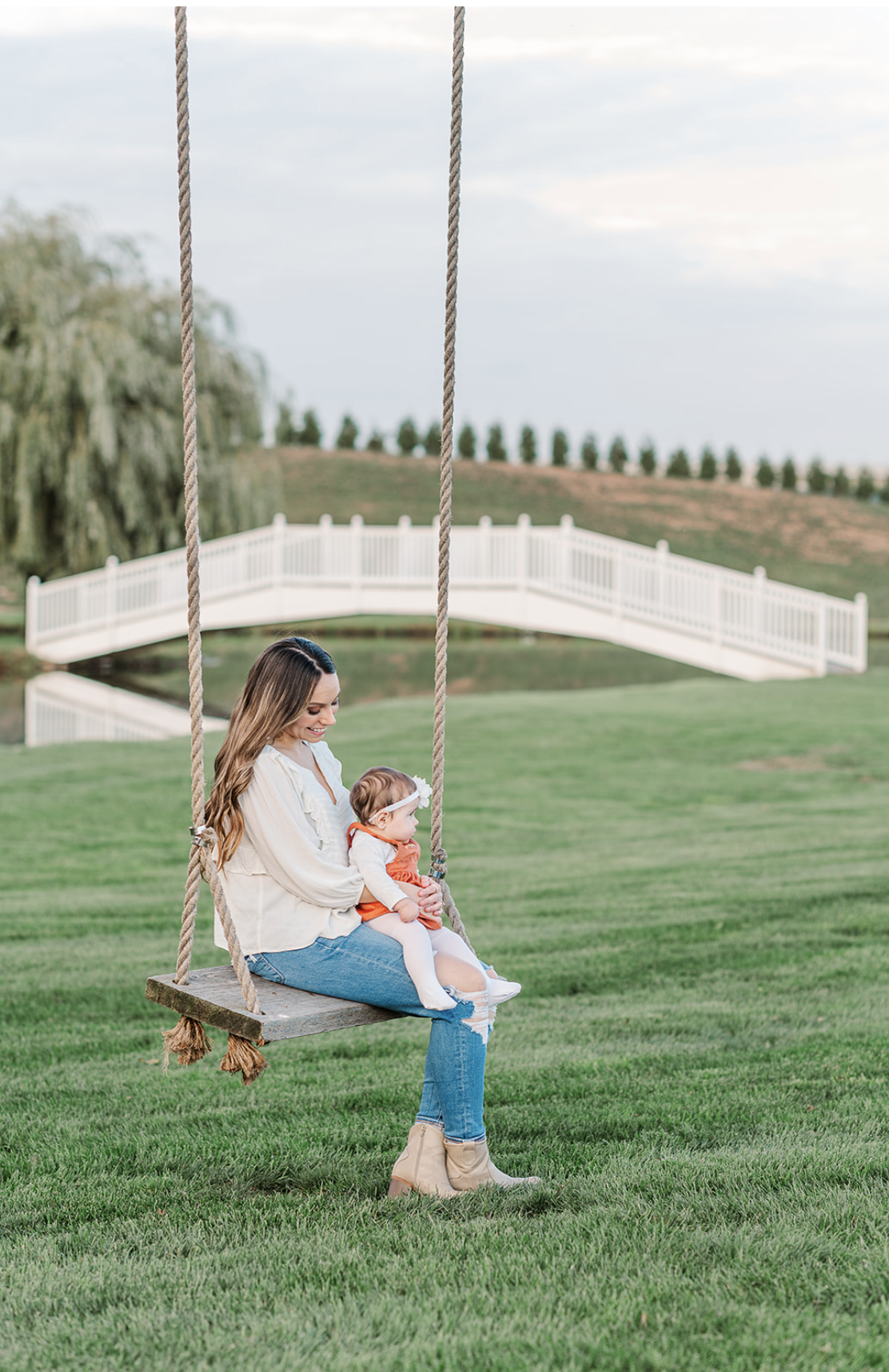 mother and daughter sitting on tree swing in front of pond and bridge at spring valley farms in dover pa