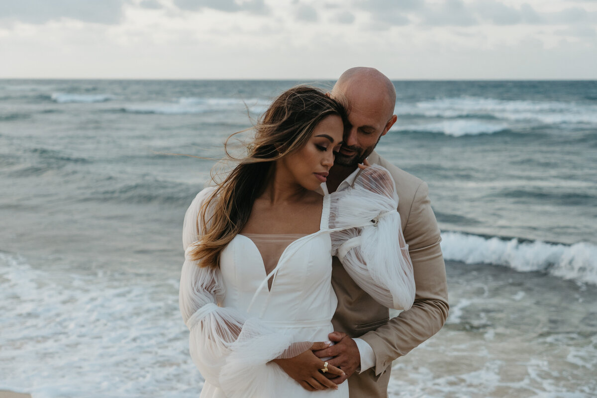Bride and groom embracing by the ocean
