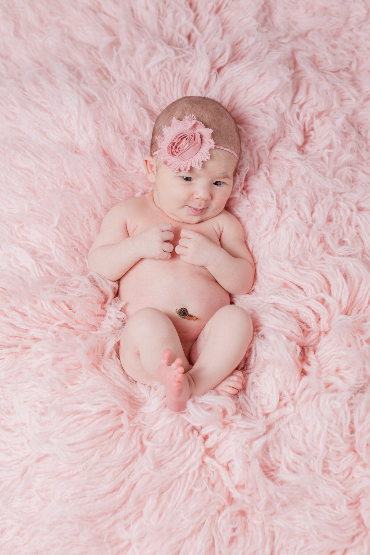 A newborn laying on a pink blanket