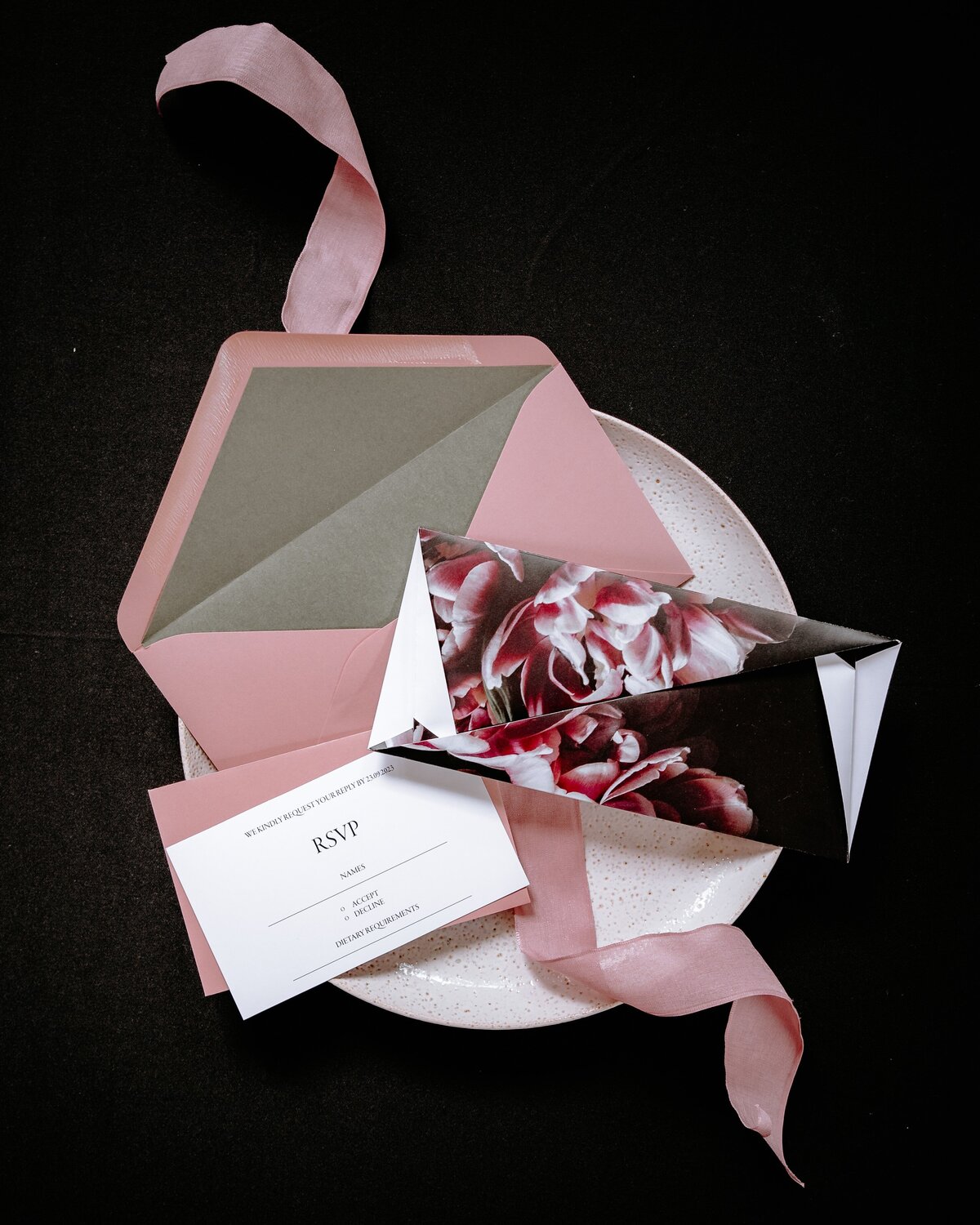 Folded origami wedding invitation with pink and moody floral graphic and pink envelope