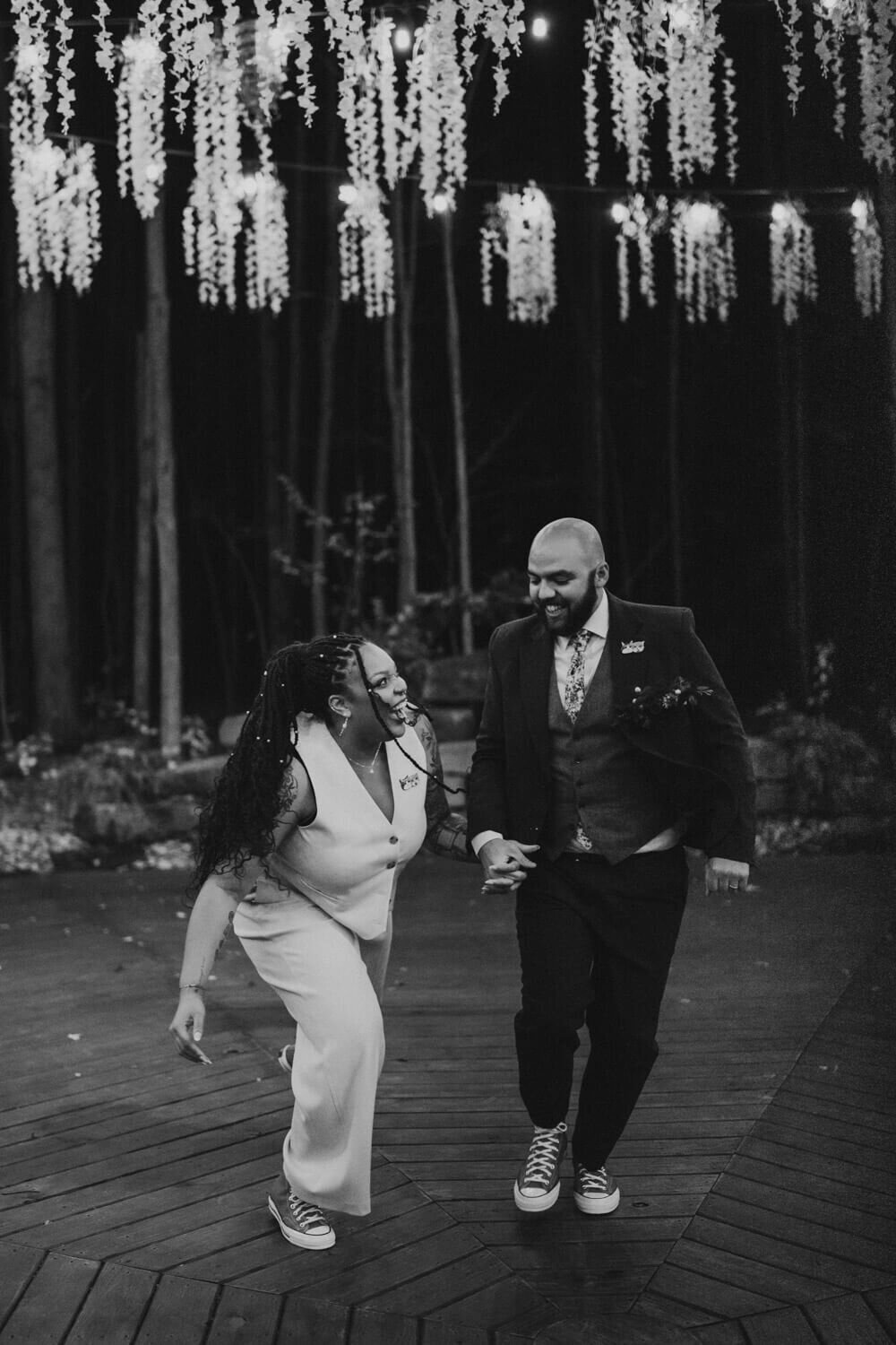 Newlyweds laugh as they take a night picture under string lights