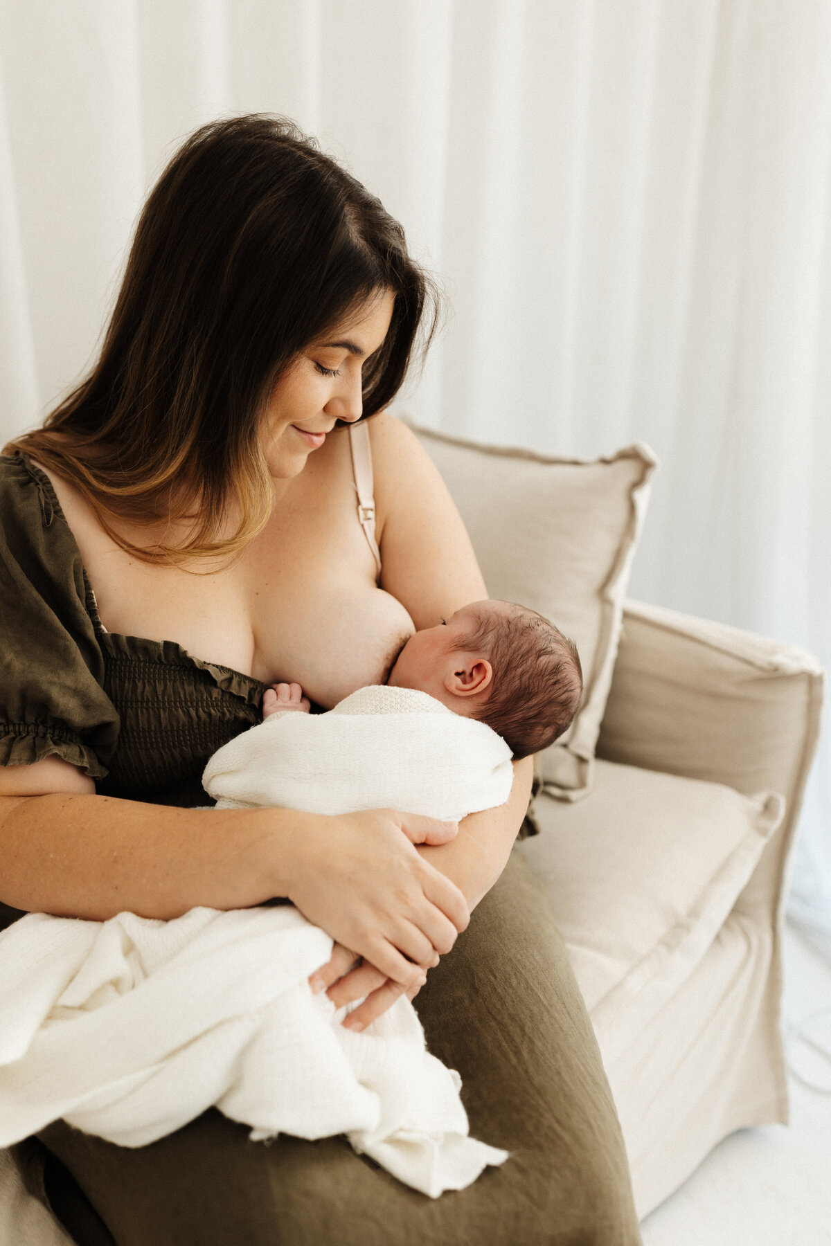 A mother breastfeeding her newborn baby during a breast feeding friendly photoshoot in christchurch