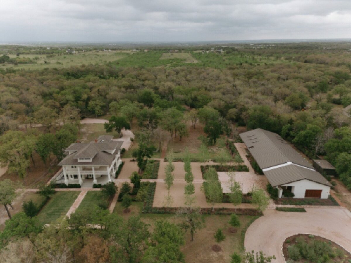 Drone view of The Grand Lady: the 1881 mansion, courtyards, flower farm and reception hall among oak trees