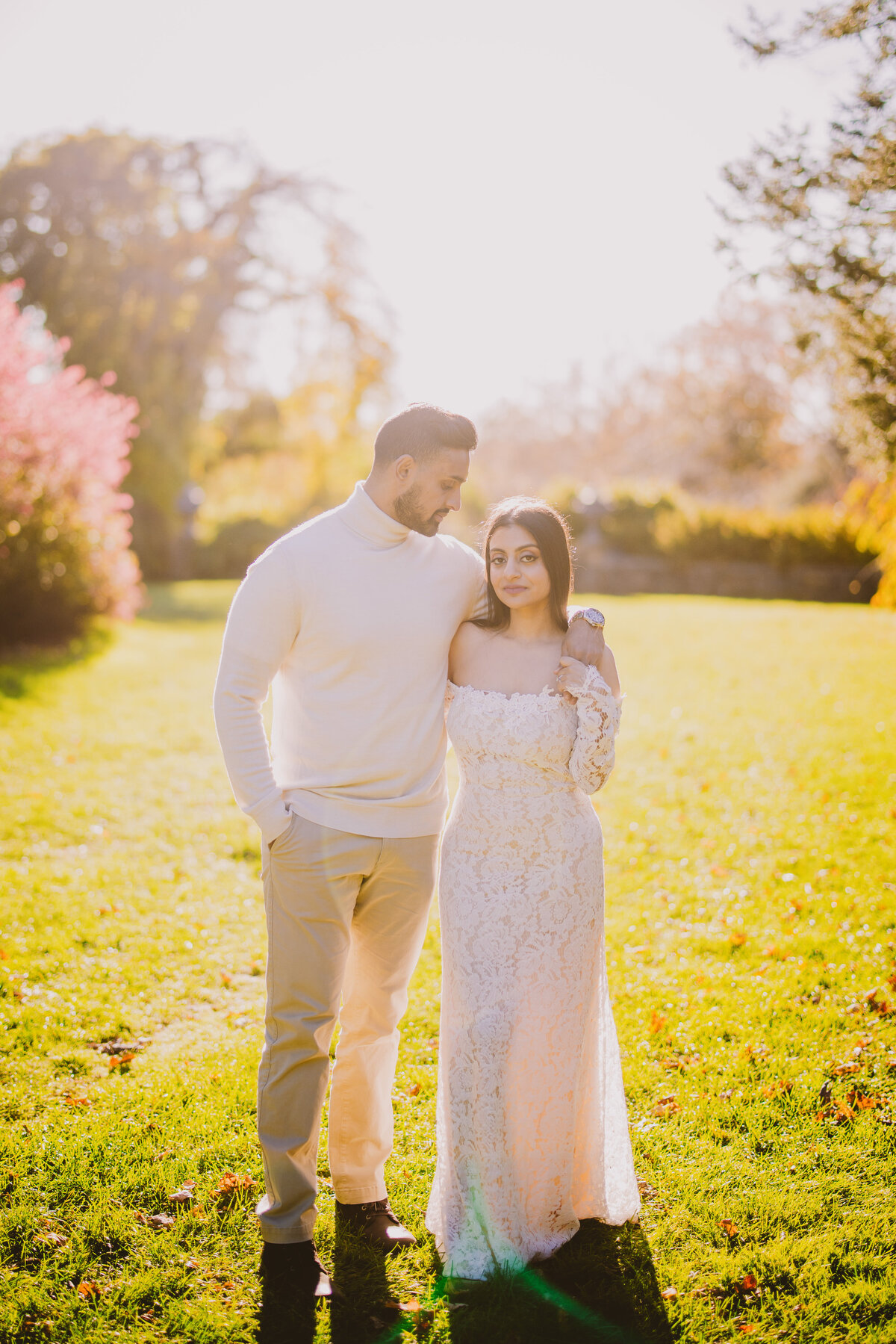 An engaged couple standing together in white outfits near skylands manor at ringwood state park in nj