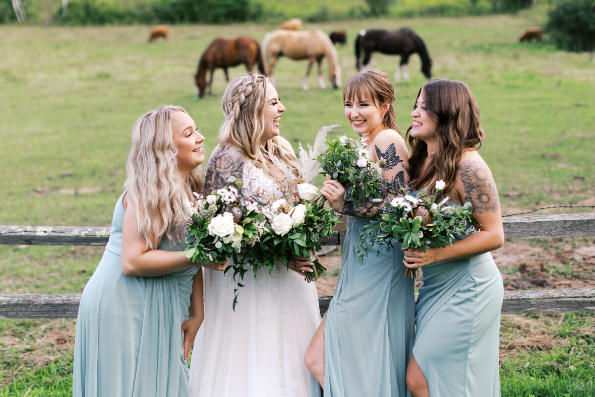 Bridesmaids sharing a joyful moment with horses in the background at a Minnesota countryside wedding | Minneapolis wedding photographer