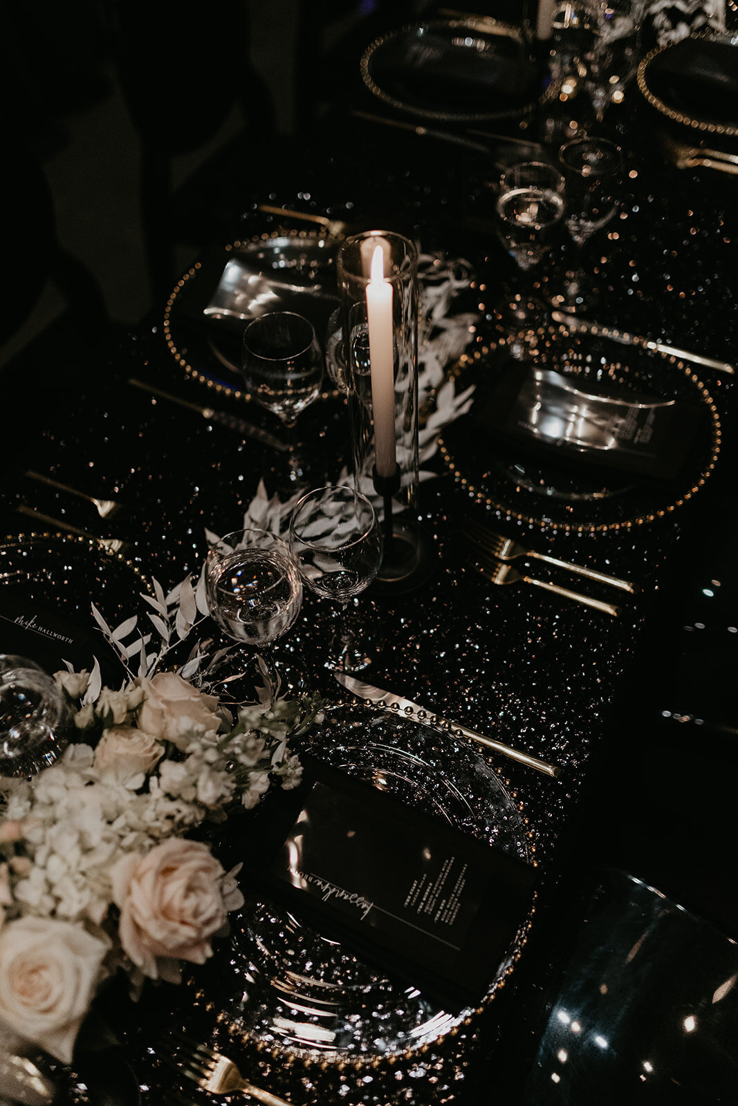 Table decor at the wedding reception features black, gold and white accents.