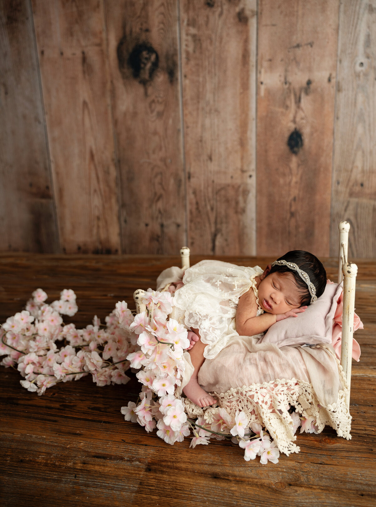 newborn baby girl on a bed with flowers