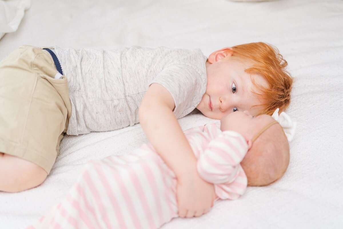 older brother hugging baby sister during Arlington, Virginia lifestyle newborn photos