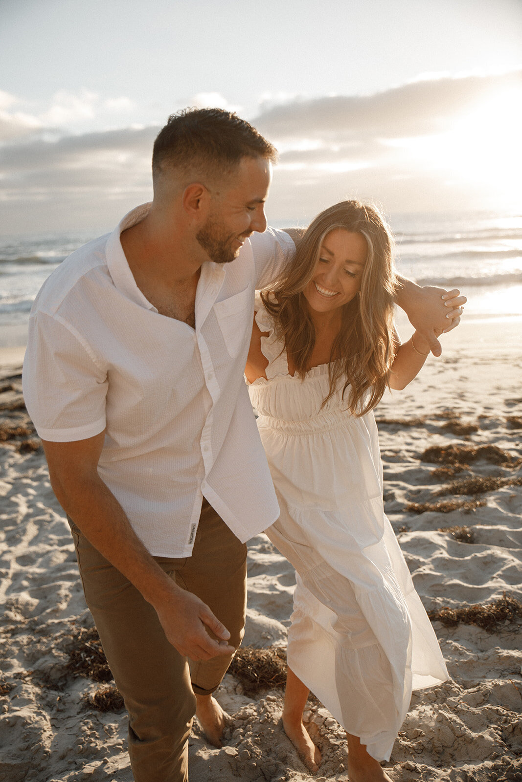 couple embrace on beach for engagement photos
