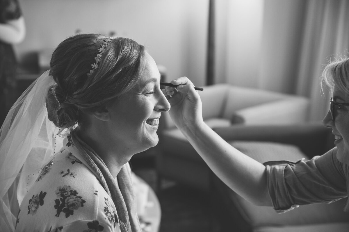 Bride putting on makeup on her wedding day.