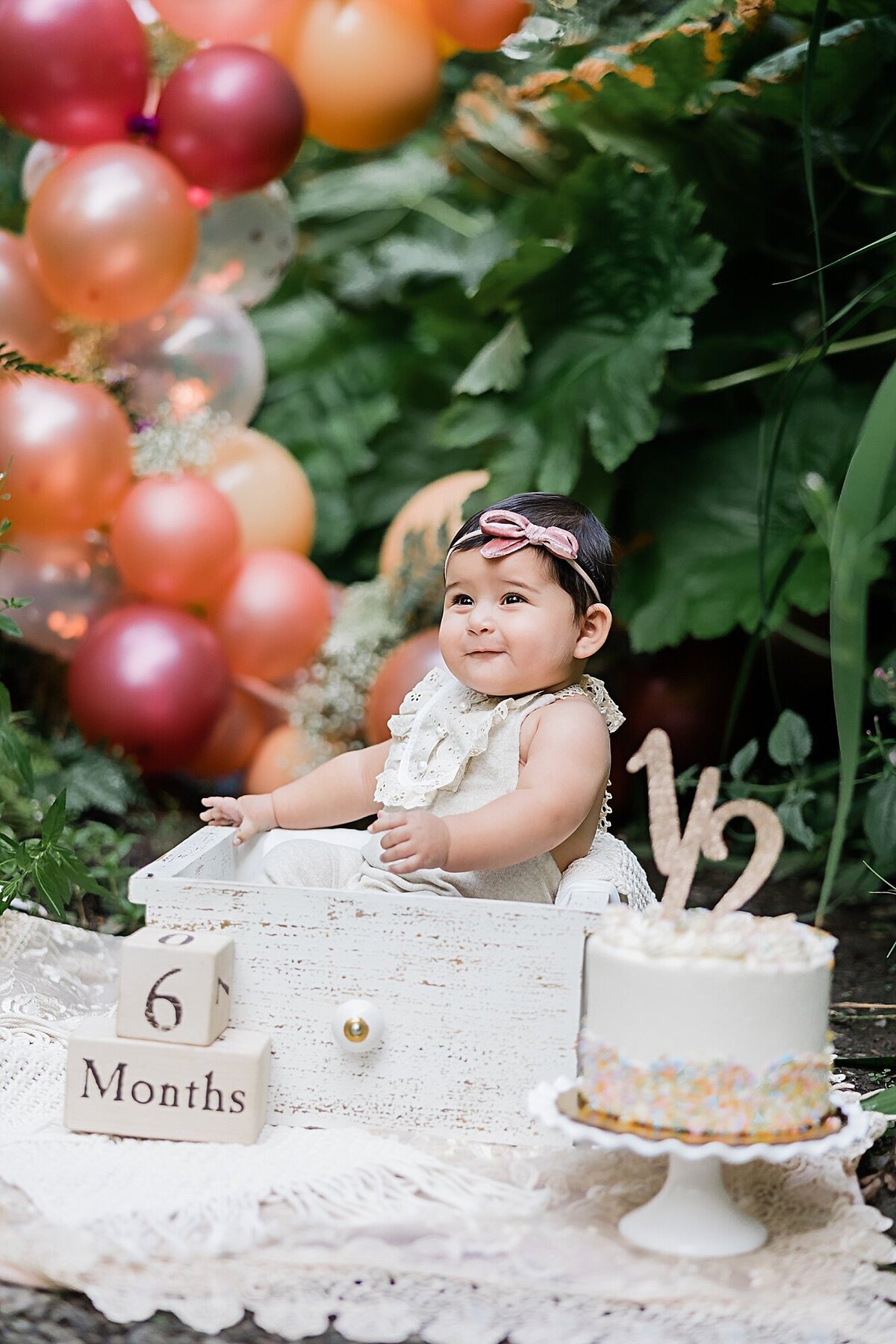 baby smiling in crate with cake outdoors for her six month pictures