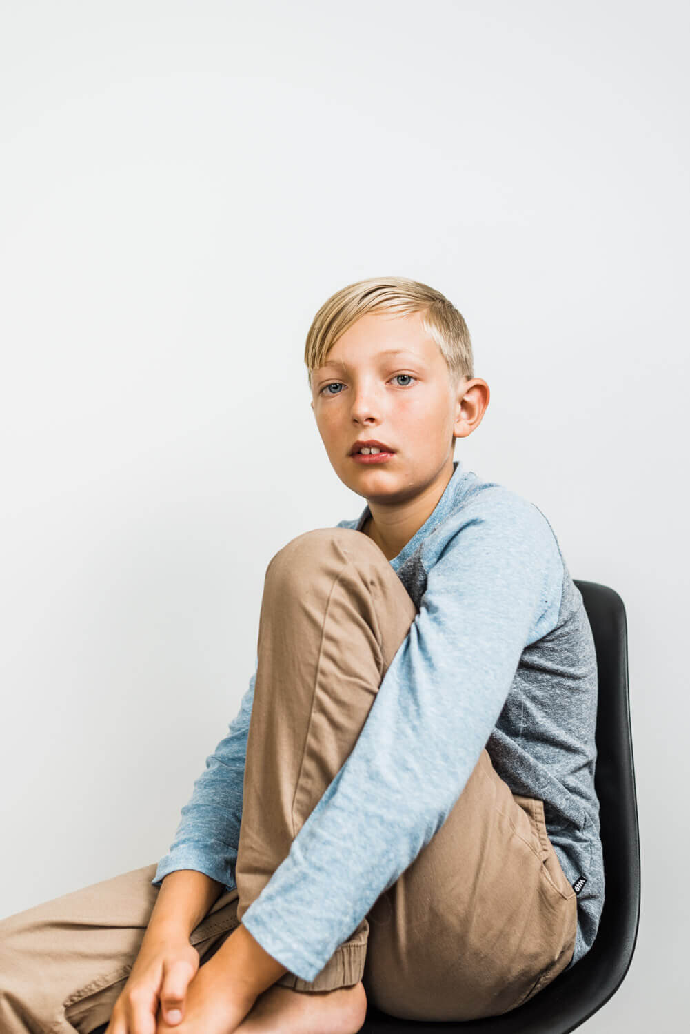 Boy sitting on chair with blank white background.