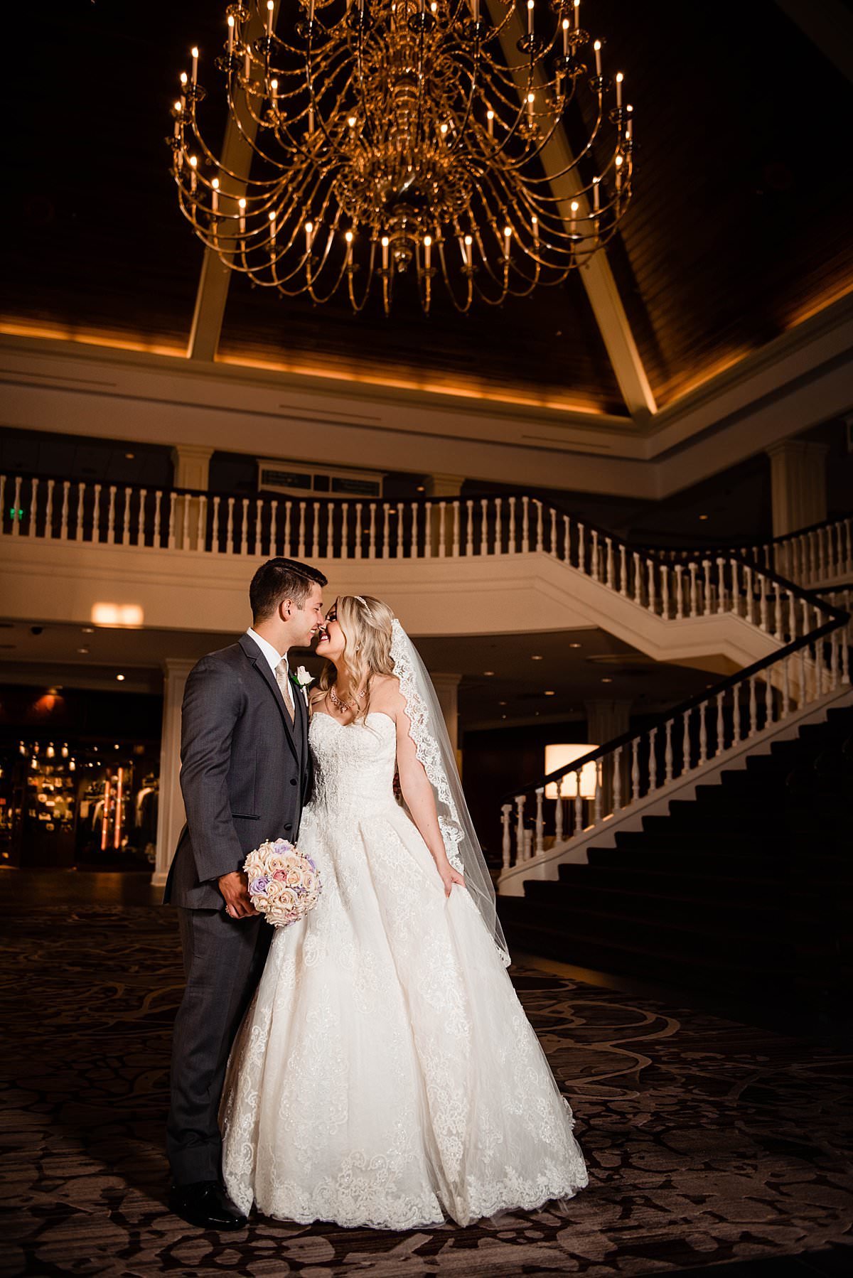 Bride and groom standing near large staircase at Gaylord Opryland with chandelier above them