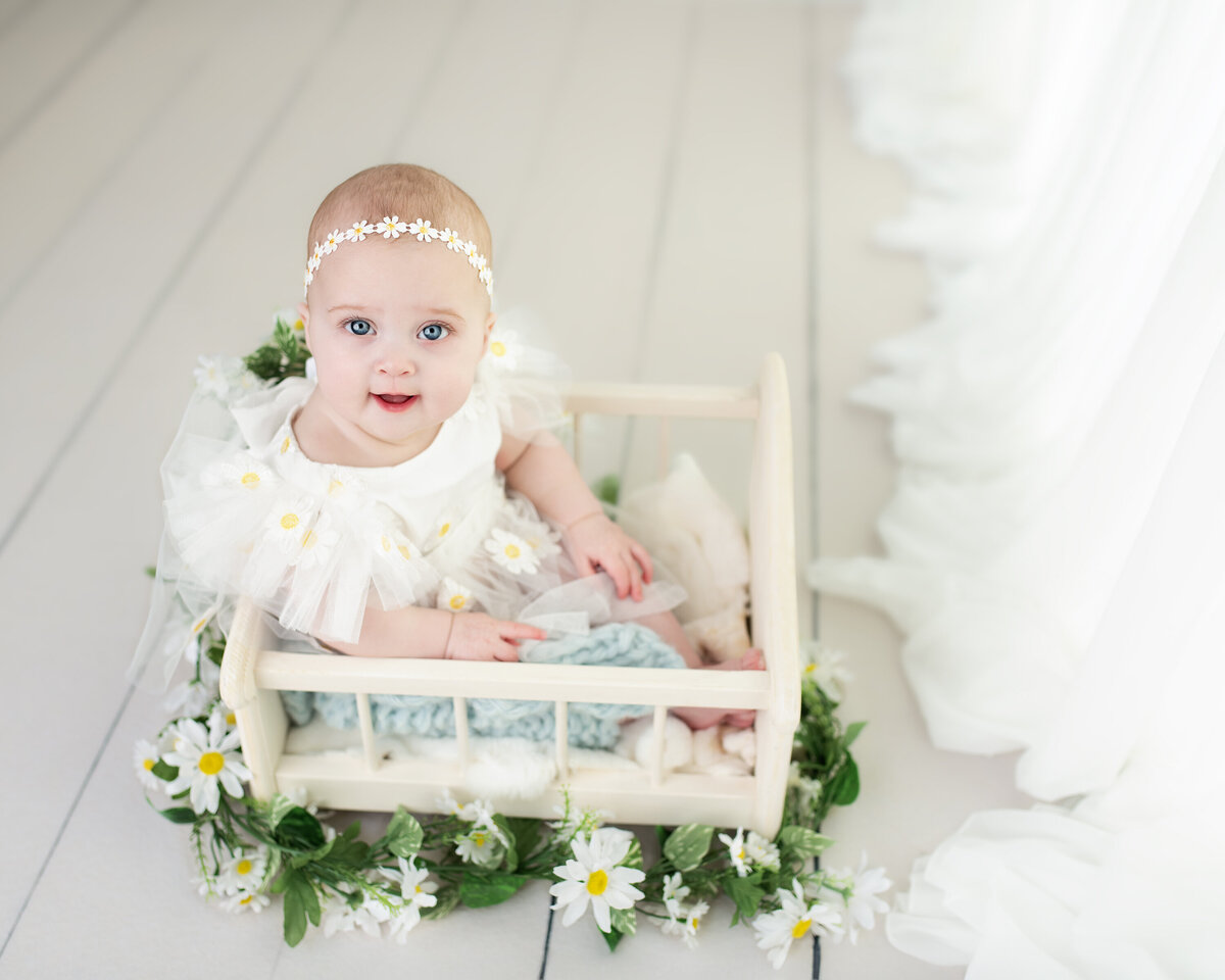  Milestone baby session featuring a daisy-themed look—captured in a soft white studio with floral charm.