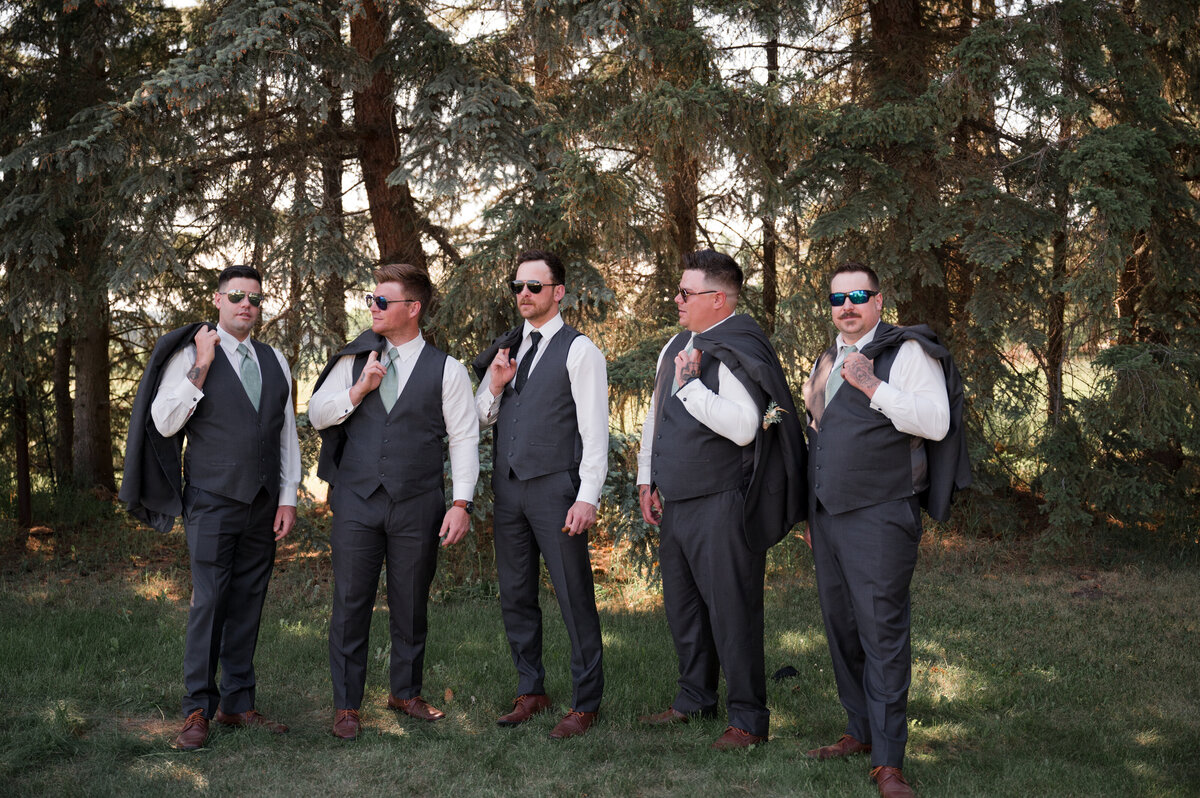 groomsmen holding their jackets over their shoulder in fun wedding day portrait