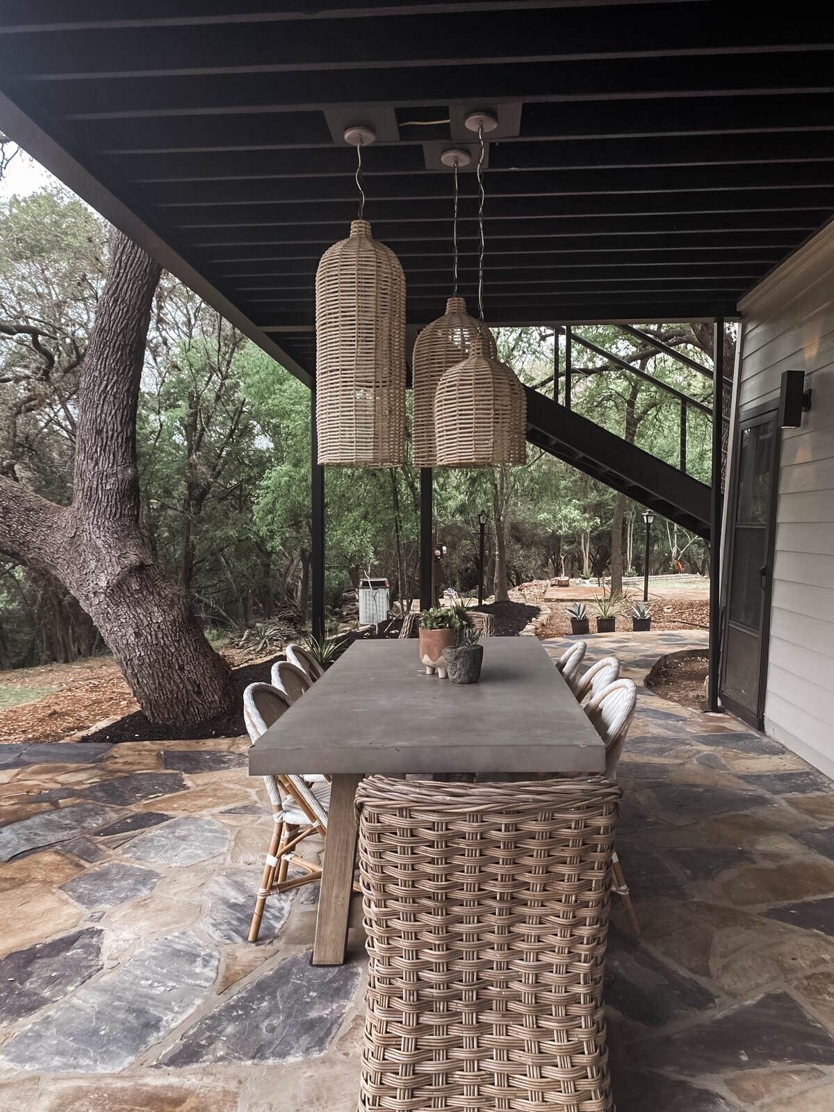 Exterior dining table with wooden lampshades hanging over table