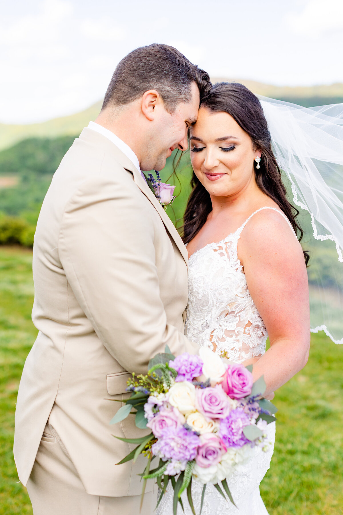 bride and groom touching foreheads with purple bouquet