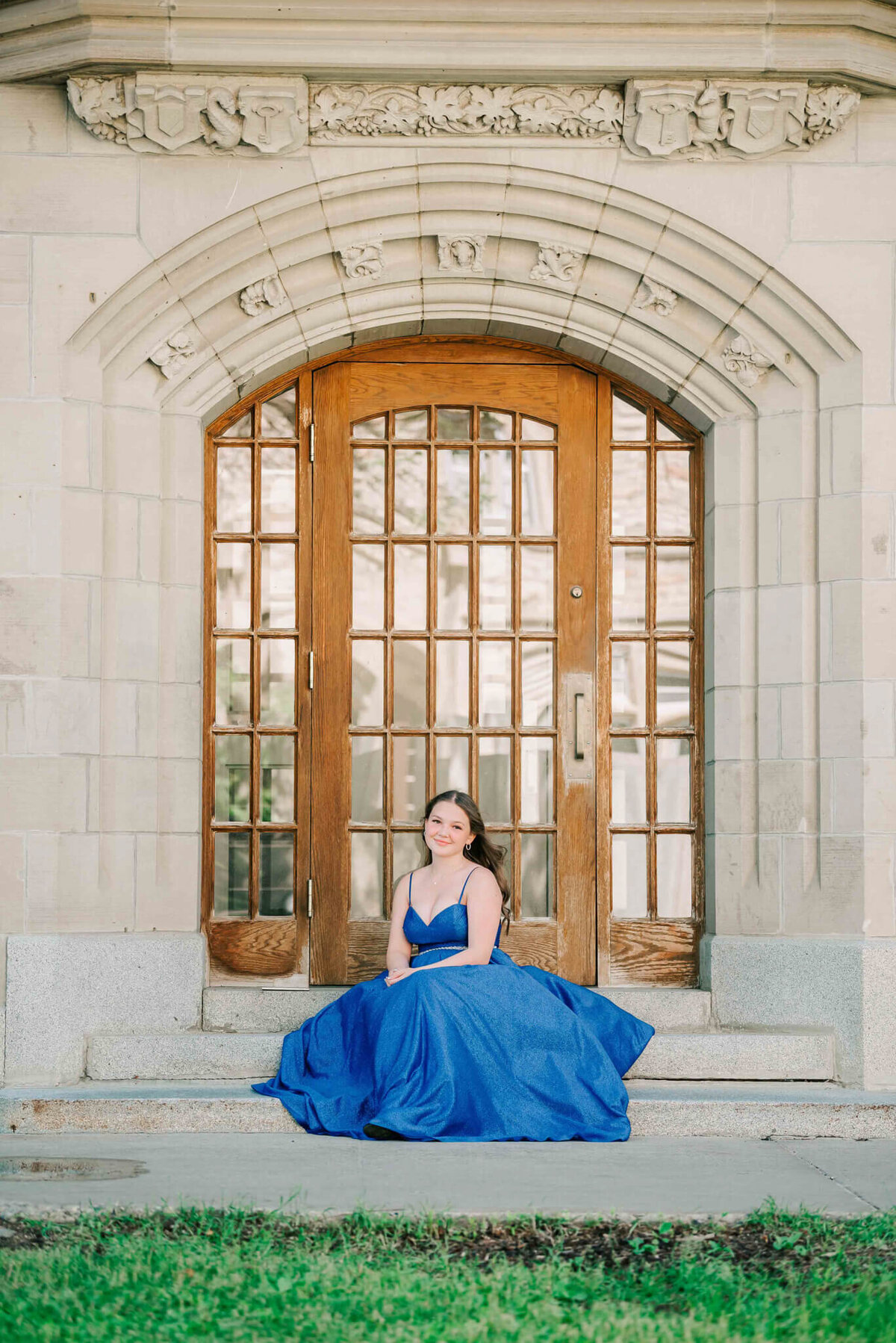 Sitting on some concrete steps in front of a large door. 