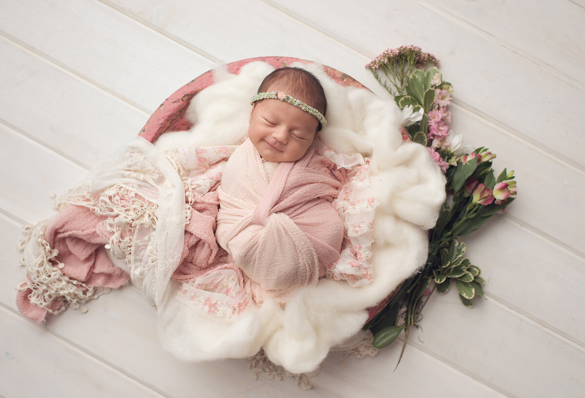 little girl with light pink blanket and full flowers next to her