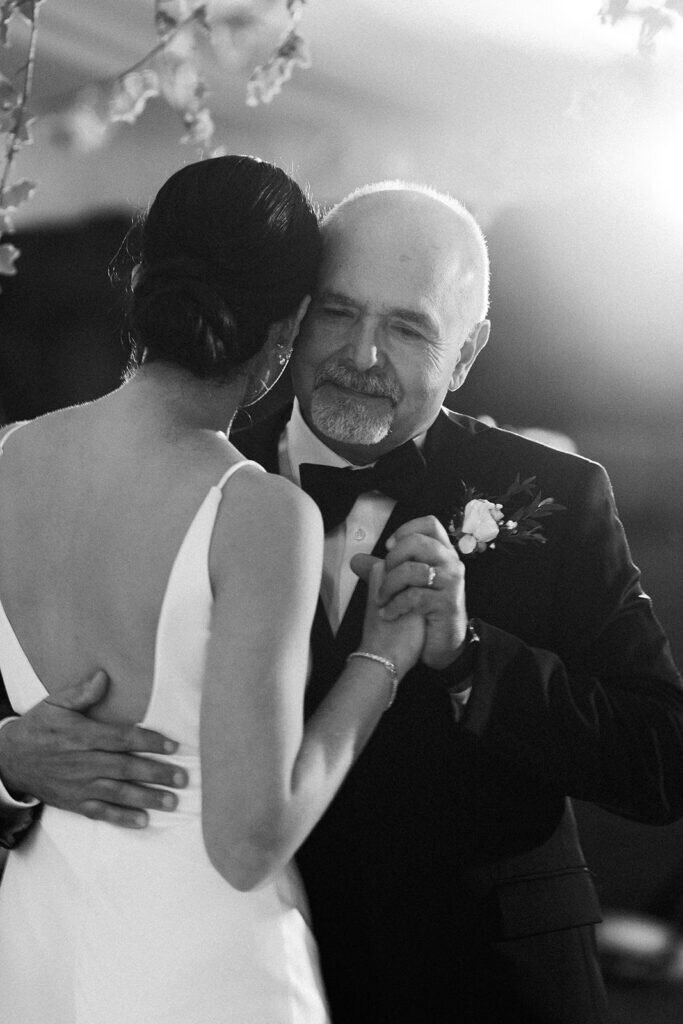 A heartfelt moment as the bride shares an emotional dance with her father, surrounded by loved ones at a beautifully decorated wedding reception in the Florida Keys. Destination wedding photography by Claudia Amalia Photography.