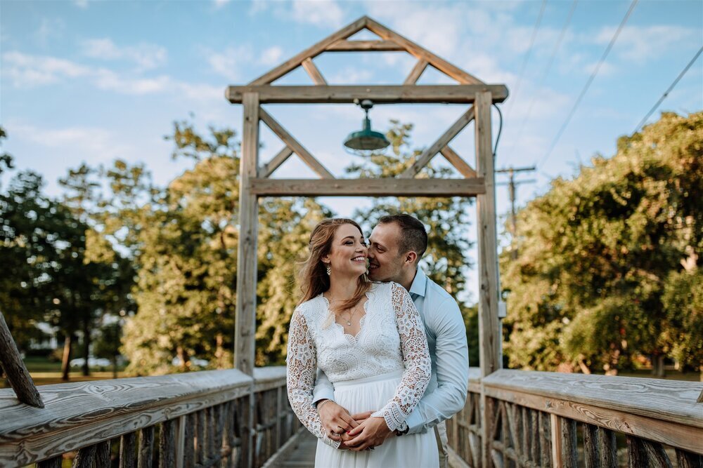 Bride and groom holding hands looking at each other while standing in front of rolling hills with the sunlight coming down on them