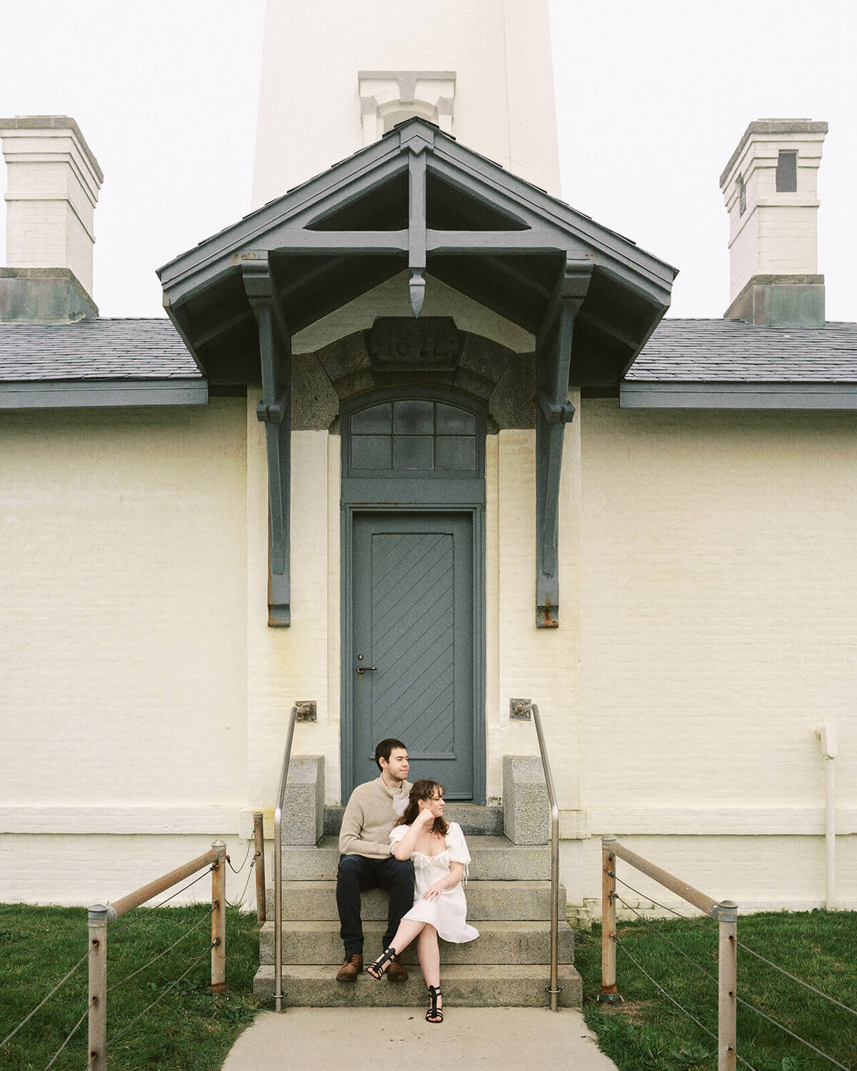 A couple sitting on the steps at Yaquina Head LIghthouse. 