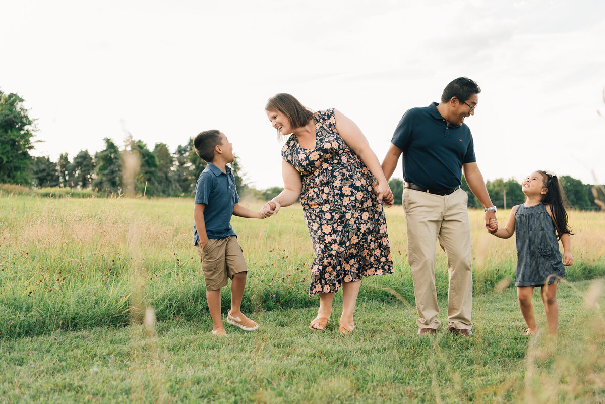 Family of four walking in field at sunset