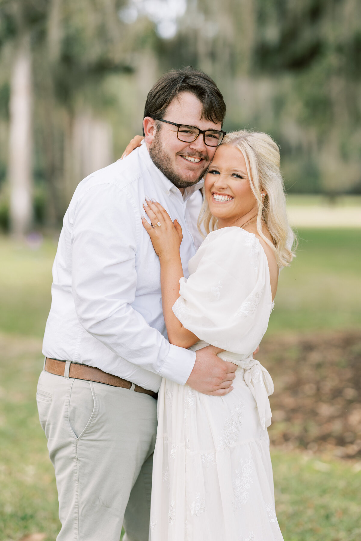engaged couple hugging in coordinating white outfits