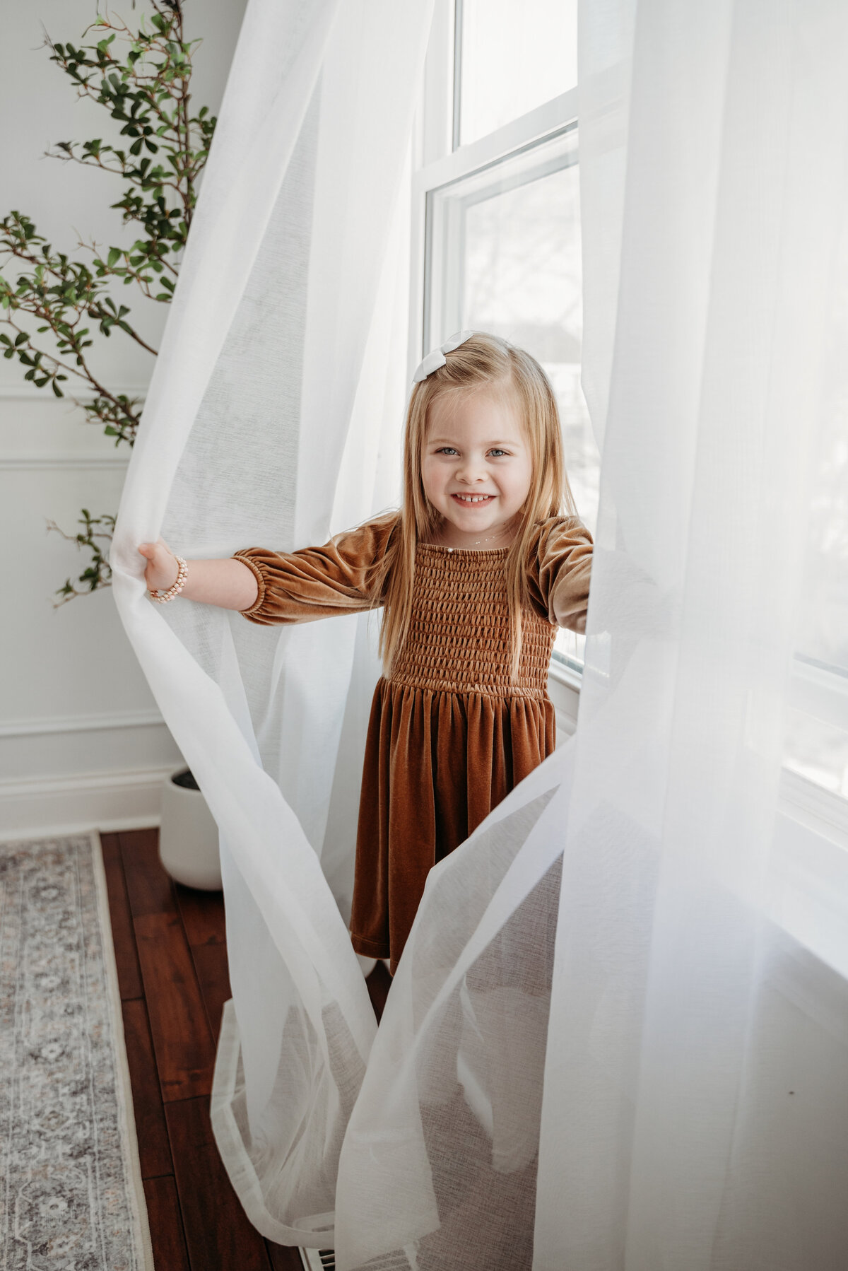 five year old girl playing peek-a-boo behind the curtain in a studio during a photoshoot, in Bartlett, IL