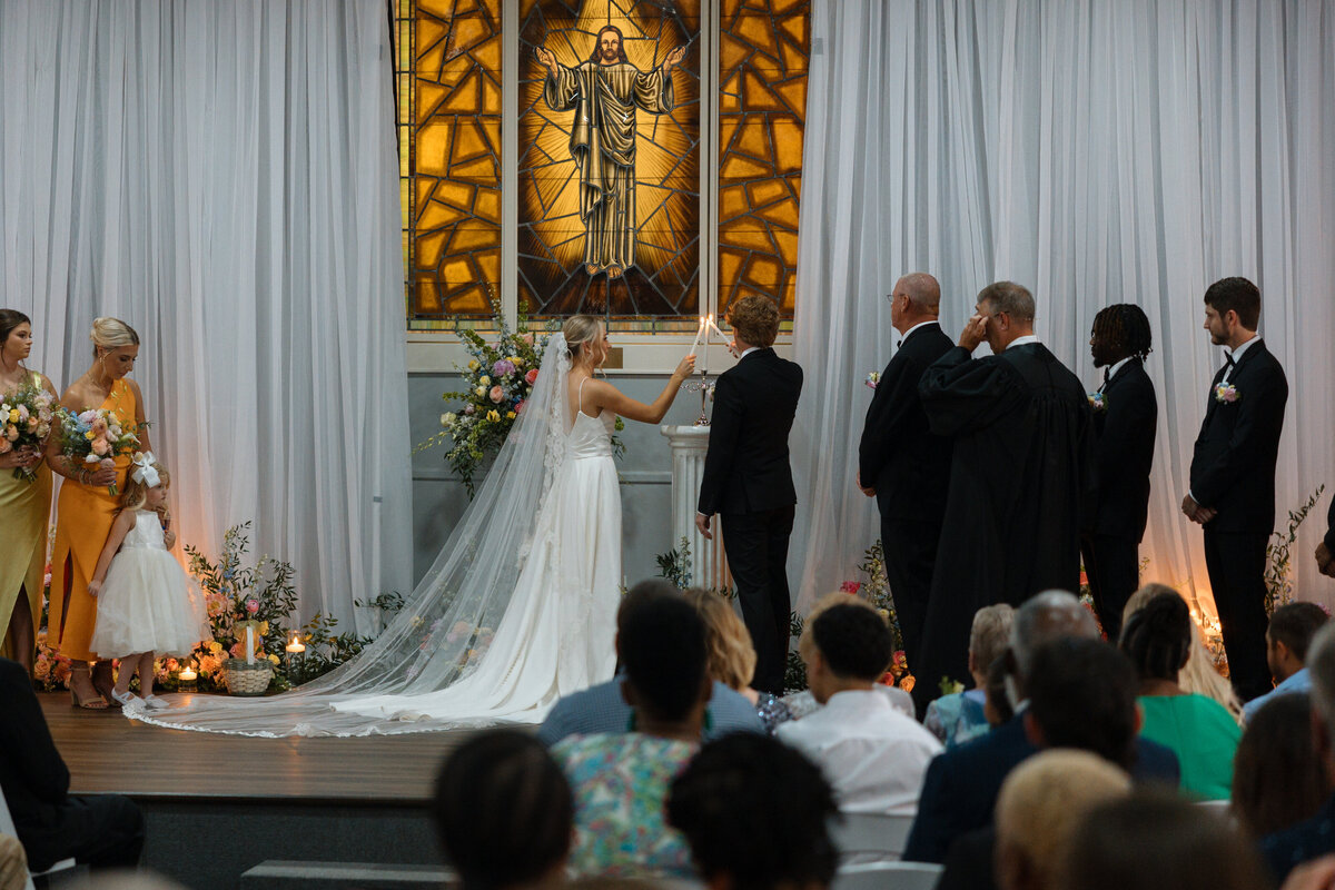 Bride and groom light a unity candle at a church