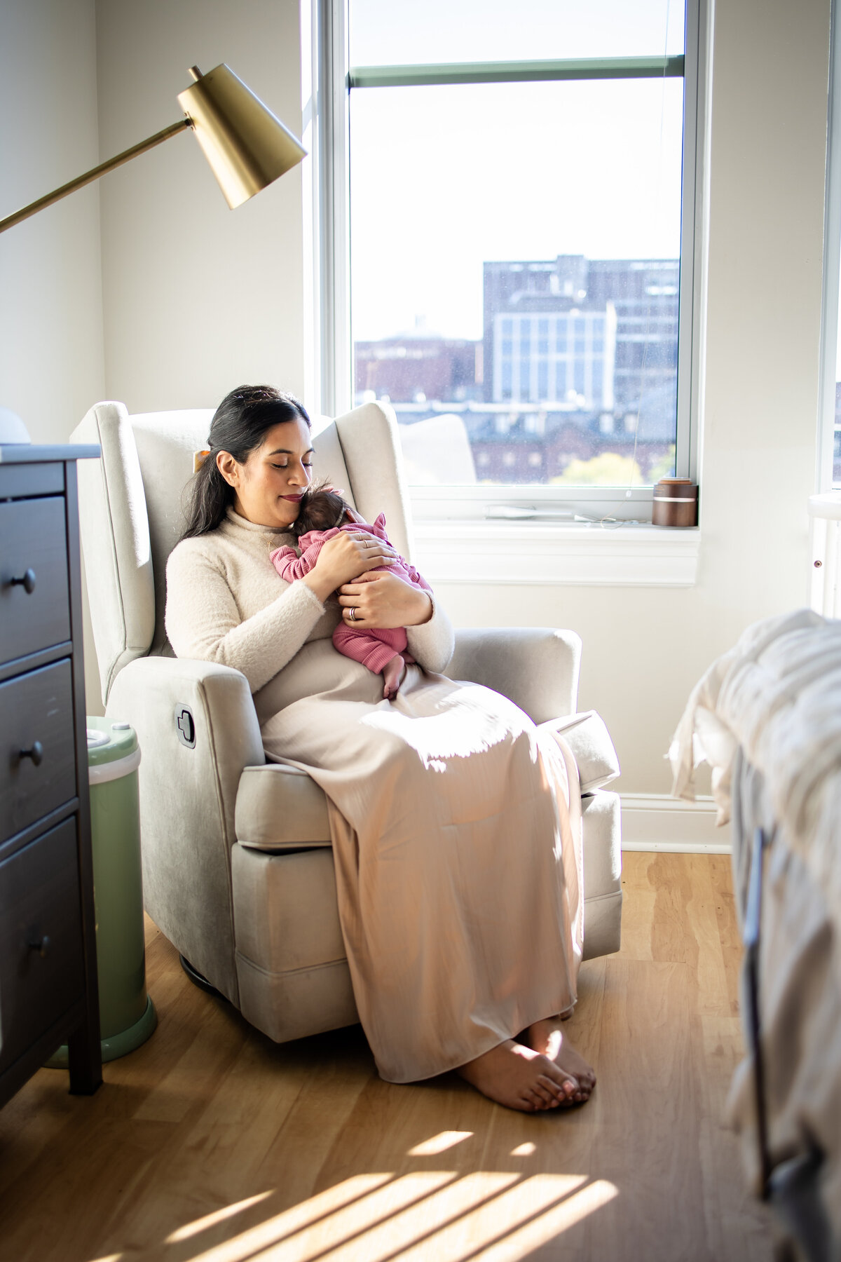 Mom rocking newborn daughter in Boston apartment