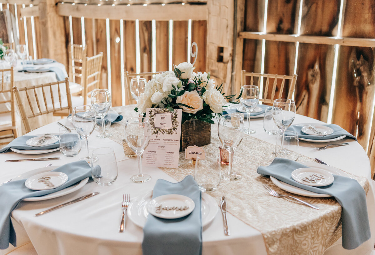 Blue and gold themed wedding dinner decor at luxurious barn reception