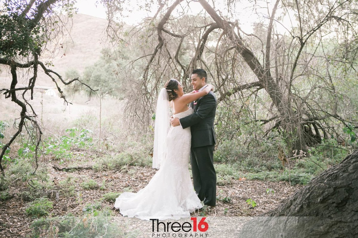 Bride and Groom embrace while walking in the woods