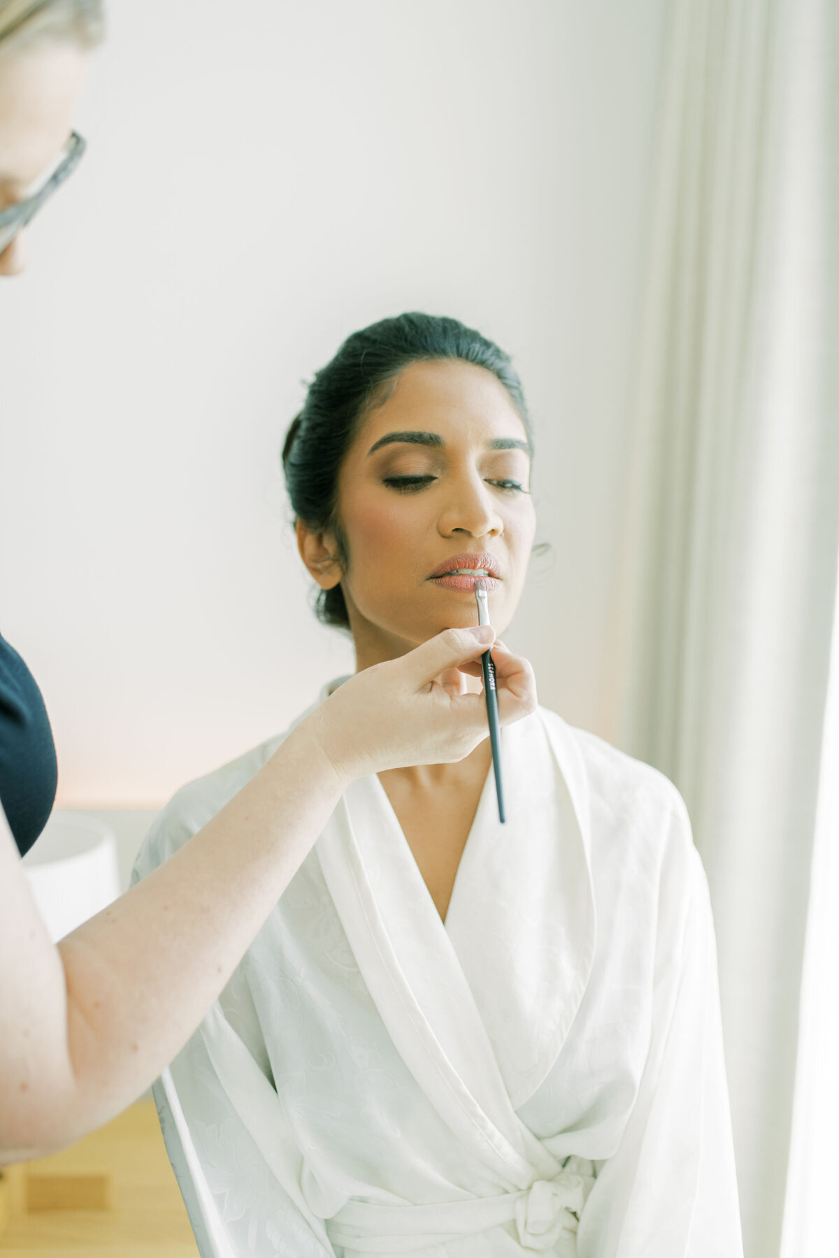 Indian woman getting her makeup done for her wedding at the pearle hotel